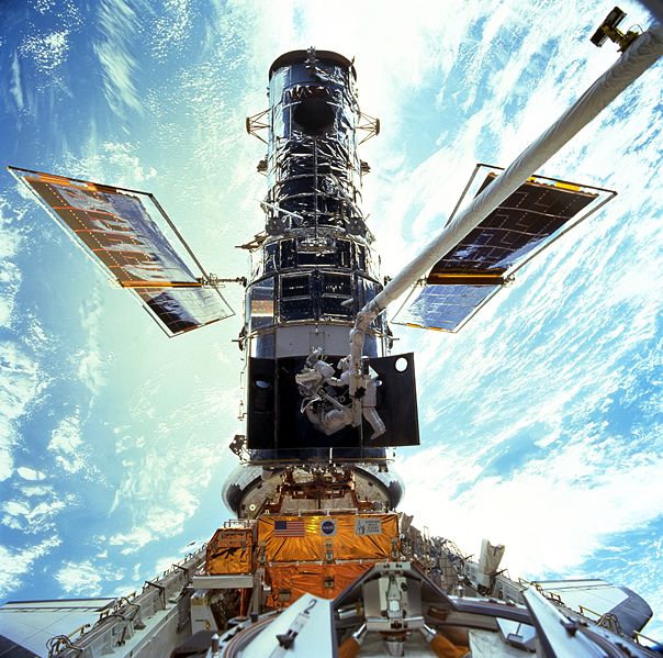 Astronauts Steven L. Smith, and John M. Grunsfeld, appear as small figures in this wide scene photographed during extravehicular activity (EVA). On this space walk they are replacing gyroscopes, contained in rate sensor units (RSU), inside the Hubble...