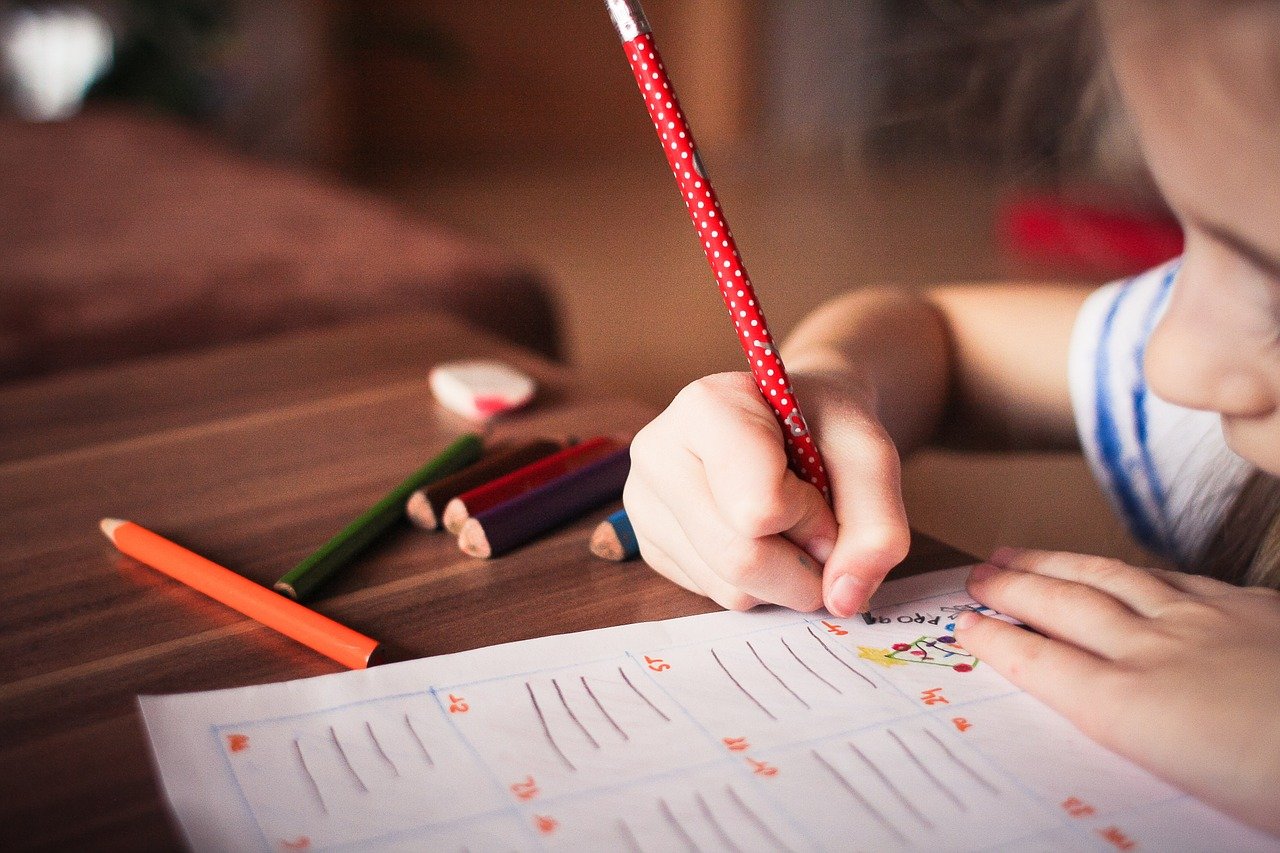 A young girl writing with a pencil.