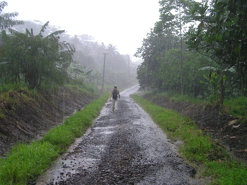 A person walking along a dirt track in the rain
