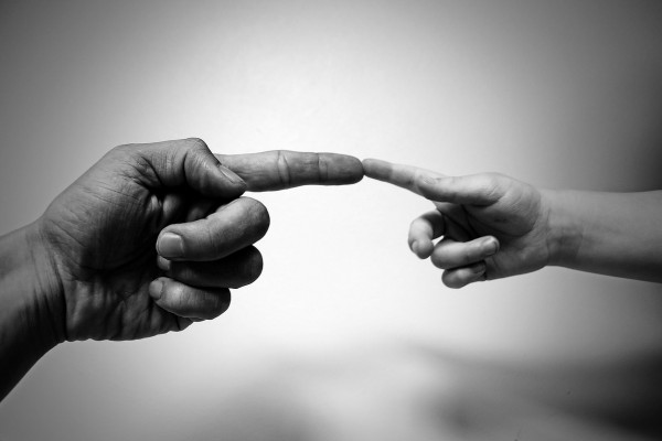 根据米开朗基罗的画作，成人的手指触摸孩子的手指