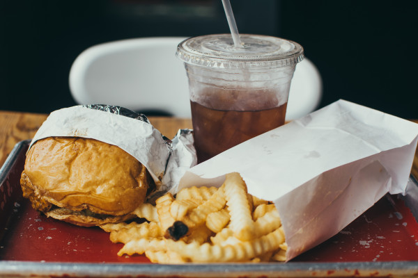 一个tray with a burger, chips, and soft drink.