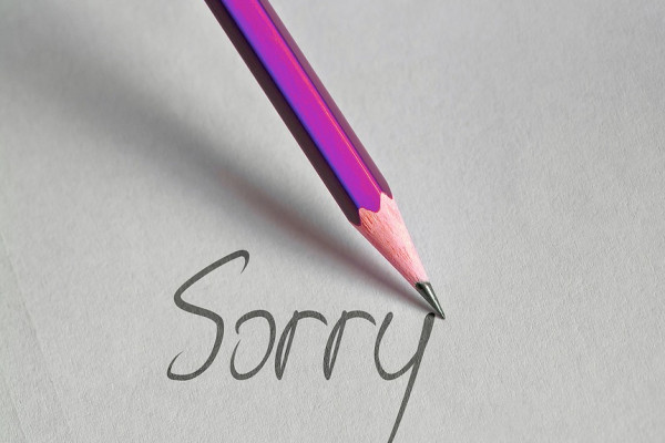 一支紫色的铅笔在纸上写着“对不起”