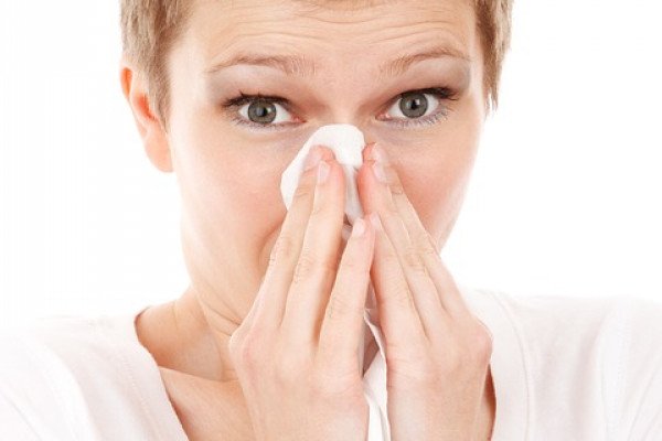 一位女士用纸巾捂住鼻子。