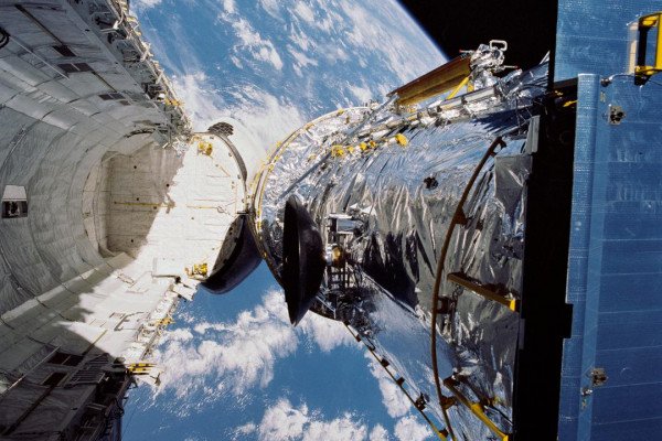 哈勃太空望远镜悬挂在距离地球332海里的发现号航天飞机货舱上方