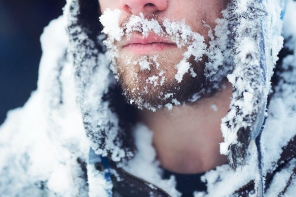 一个留着胡子的男人穿着一件被冰覆盖的冬衣。