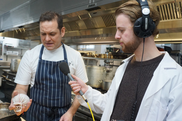Chef Tristan Welch holding a haggis while Phil Sansom holds a microphone to his mouth