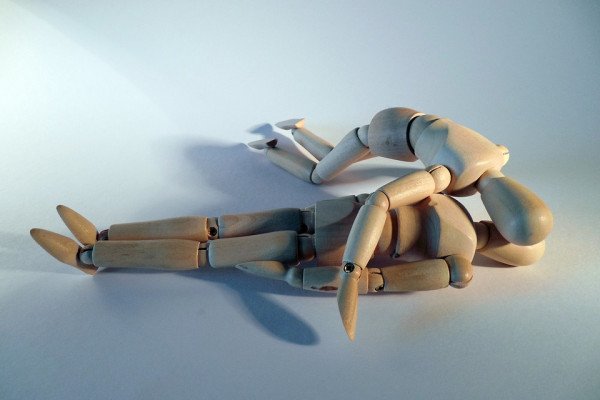 这是一张木制玩偶给另一个木制玩偶做心肺复苏的照片