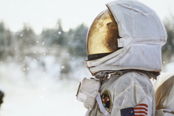 一位宇航员在雪地里侧影，仰望天空