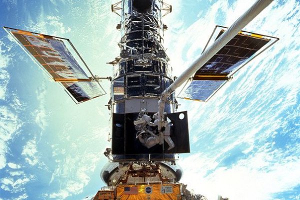 宇航员史蒂文·l·史密斯和约翰·m·格伦斯菲尔德在舱外活动(EVA)期间拍摄的这幅广角照片中显得很渺小。在这次太空行走中，他们正在更换哈勃望远镜内部速率传感器单元(RSU)中的陀螺仪。