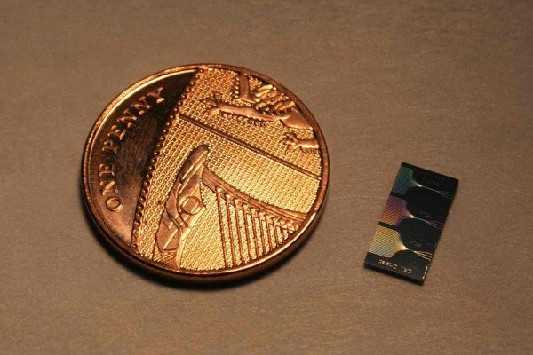 英国便士旁边的光子芯片。该芯片包含微米和亚微米特征，并使用波导网络引导光。该网络的输出可以在芯片表面看到。