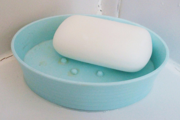 一块白色的肥皂放在浅蓝色的塑料肥皂盘里。