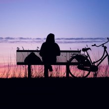 一个女人坐在公园的长椅上看日落