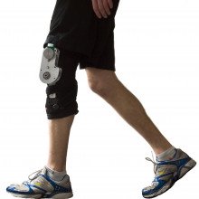 The biomechanical energy harvester comprises an aluminium chassis and generator (cylindrical component at the top of the chassis with green plastic attached) mounted on a customized orthopaedic knee brace (black), totalling 1.6 kg mass.