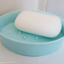 一块白色的肥皂放在浅蓝色的塑料肥皂盘里。